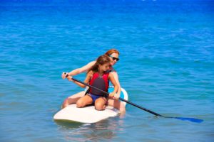 mother and daughter paddle boarding on vacation in hilton head island. 